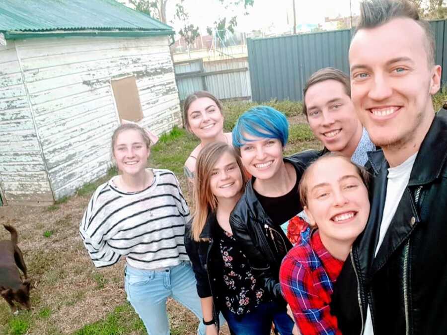 Woman with blue hair stands with friends