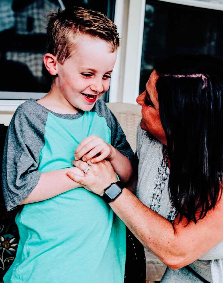 Mom puts hand on smiling son's chest