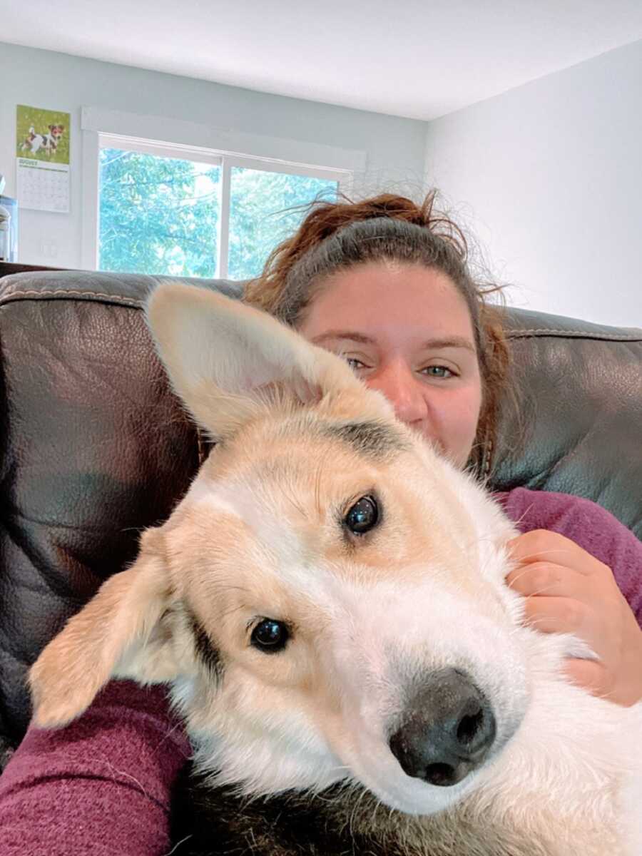 Woman sits on couch with big dog's head on lap