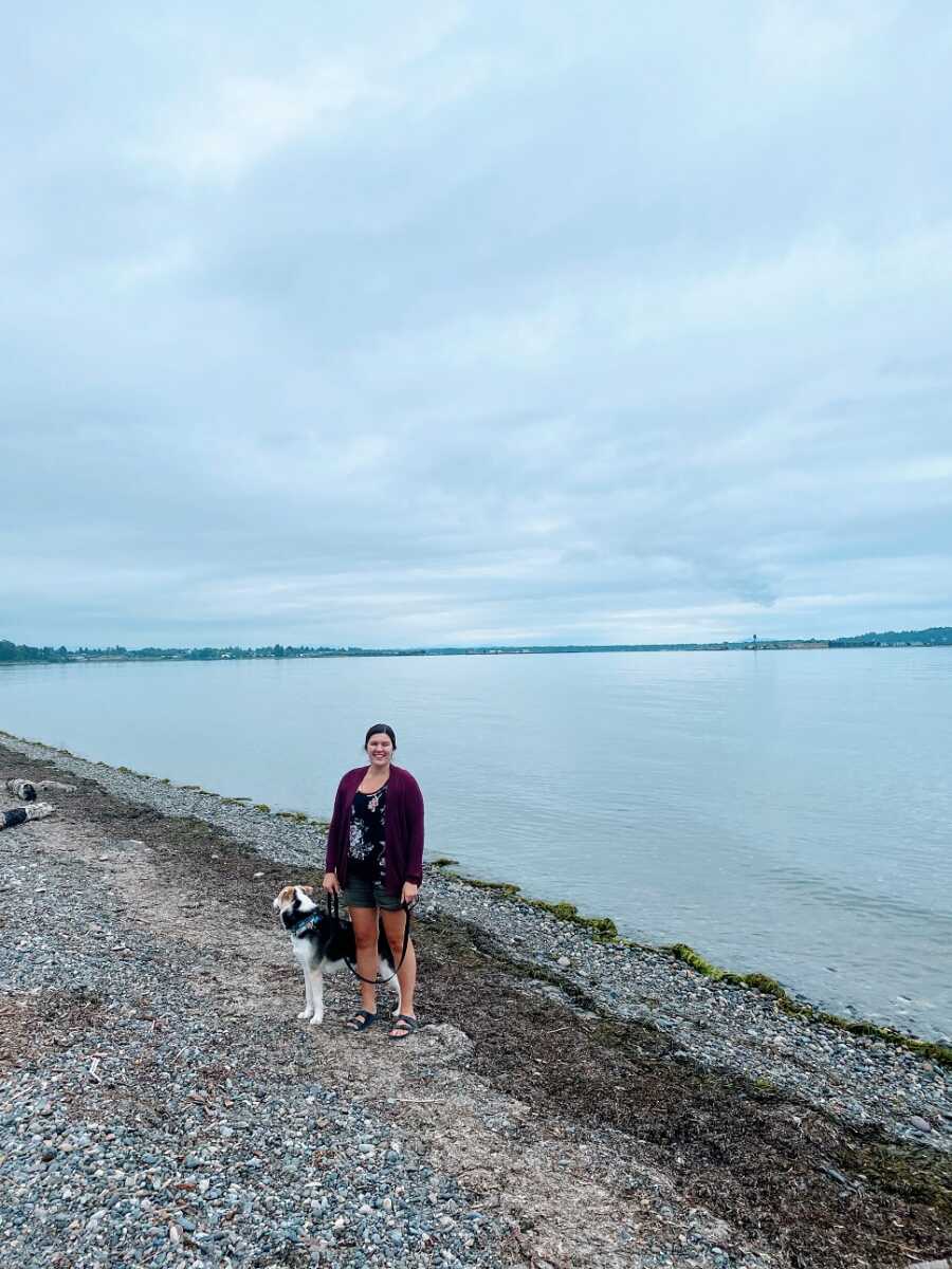 Woman stands with dog on the beach