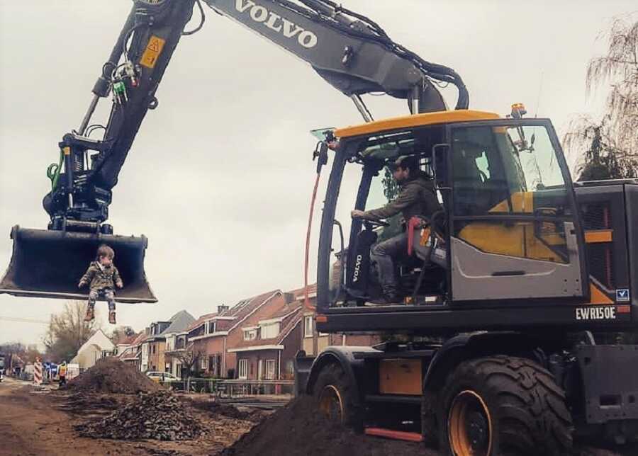 Dad creates picture scooping toddler up with construction excavator.