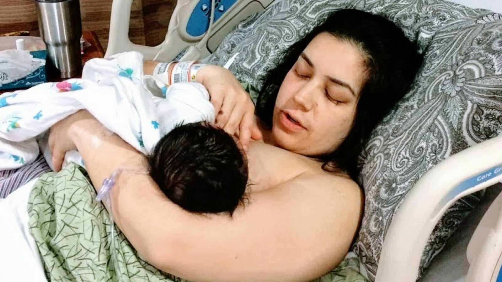 Woman lies in hospital bed breastfeeding baby
