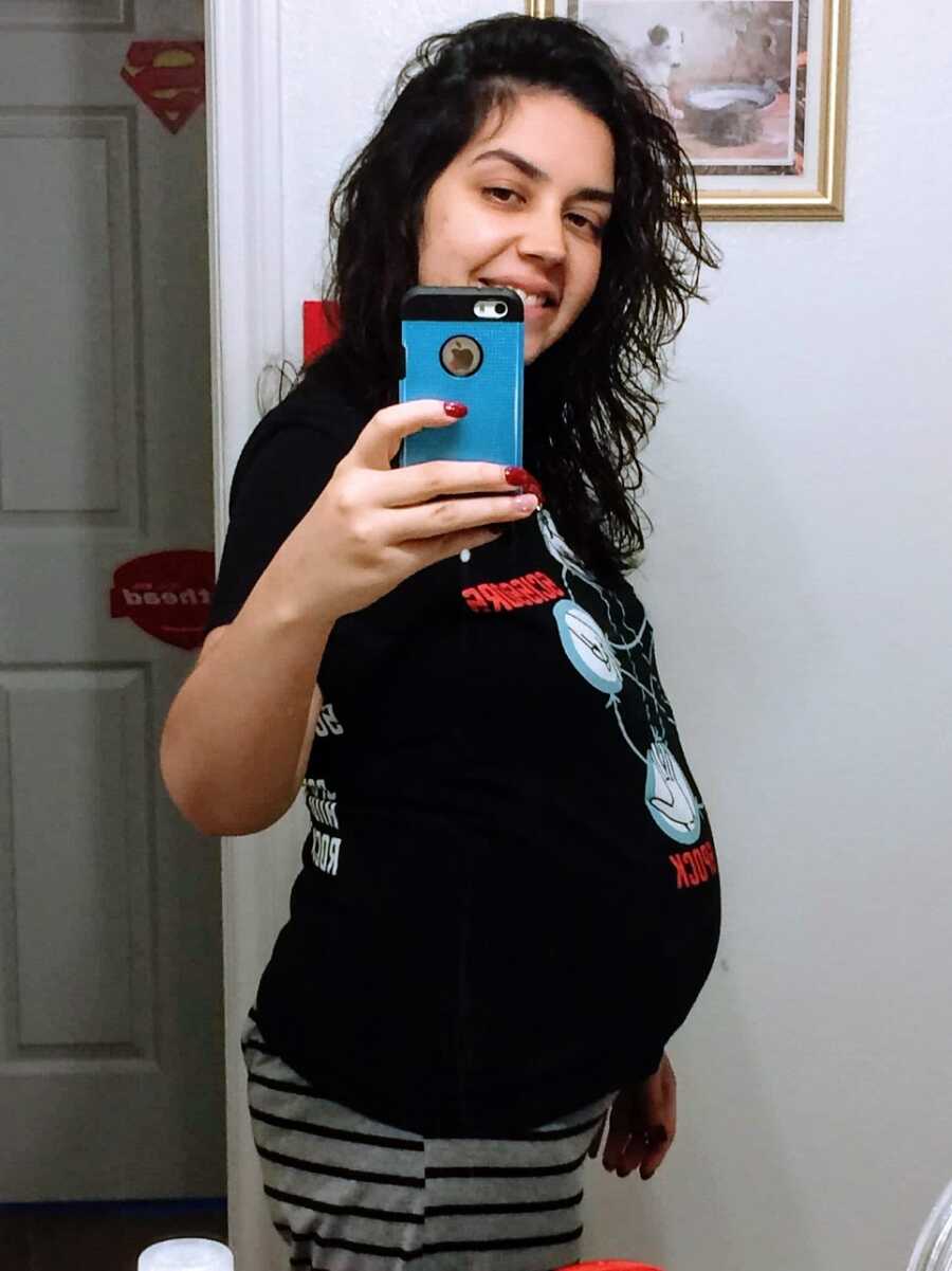 Pregnant woman holds phone to take picture