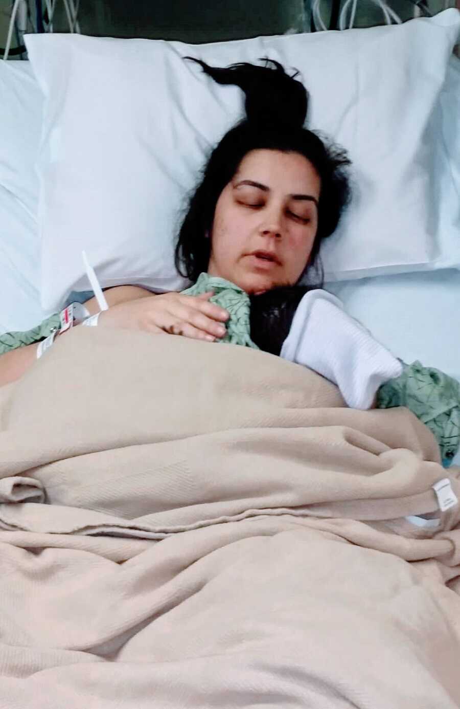 Mother lying in hospital bed with newborn baby