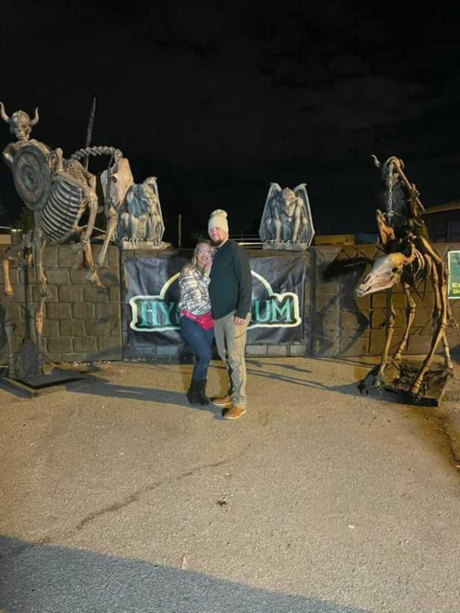 Young couple in a blended family take a photo together outside of an outdoor haunted experience in Indiana to celebrate Halloween
