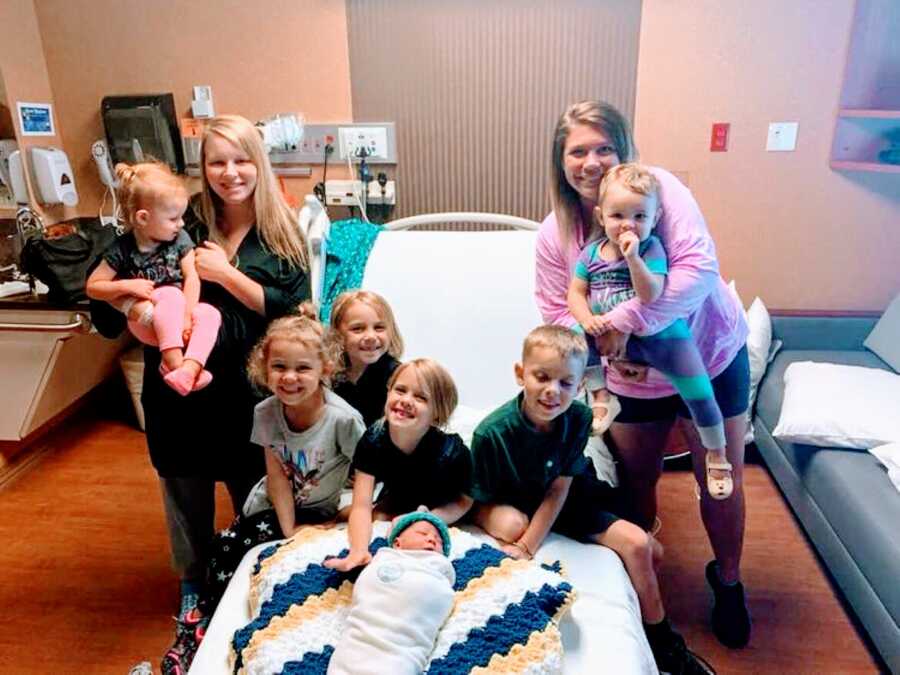 Two moms take a family photo in the hospital together with their combined seven children
