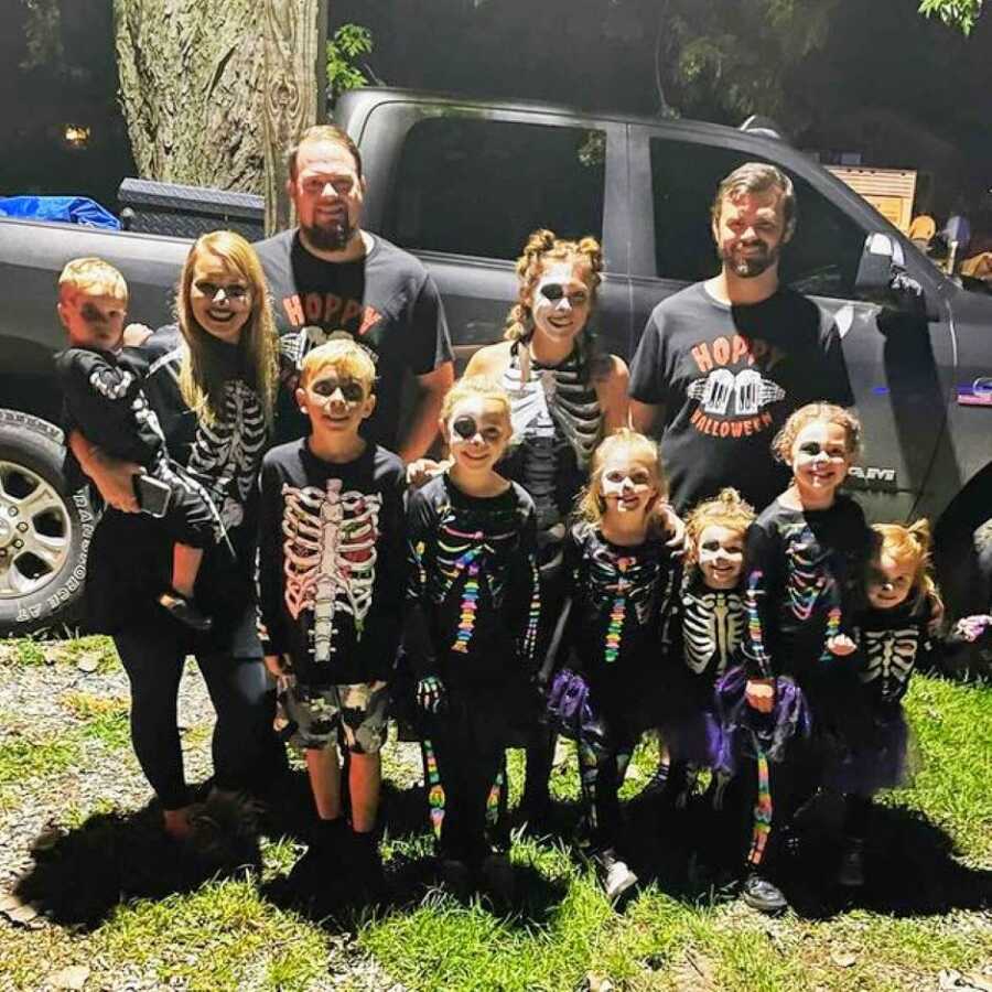 Blended family take a group photo together while all wearing matching costumes for Halloween