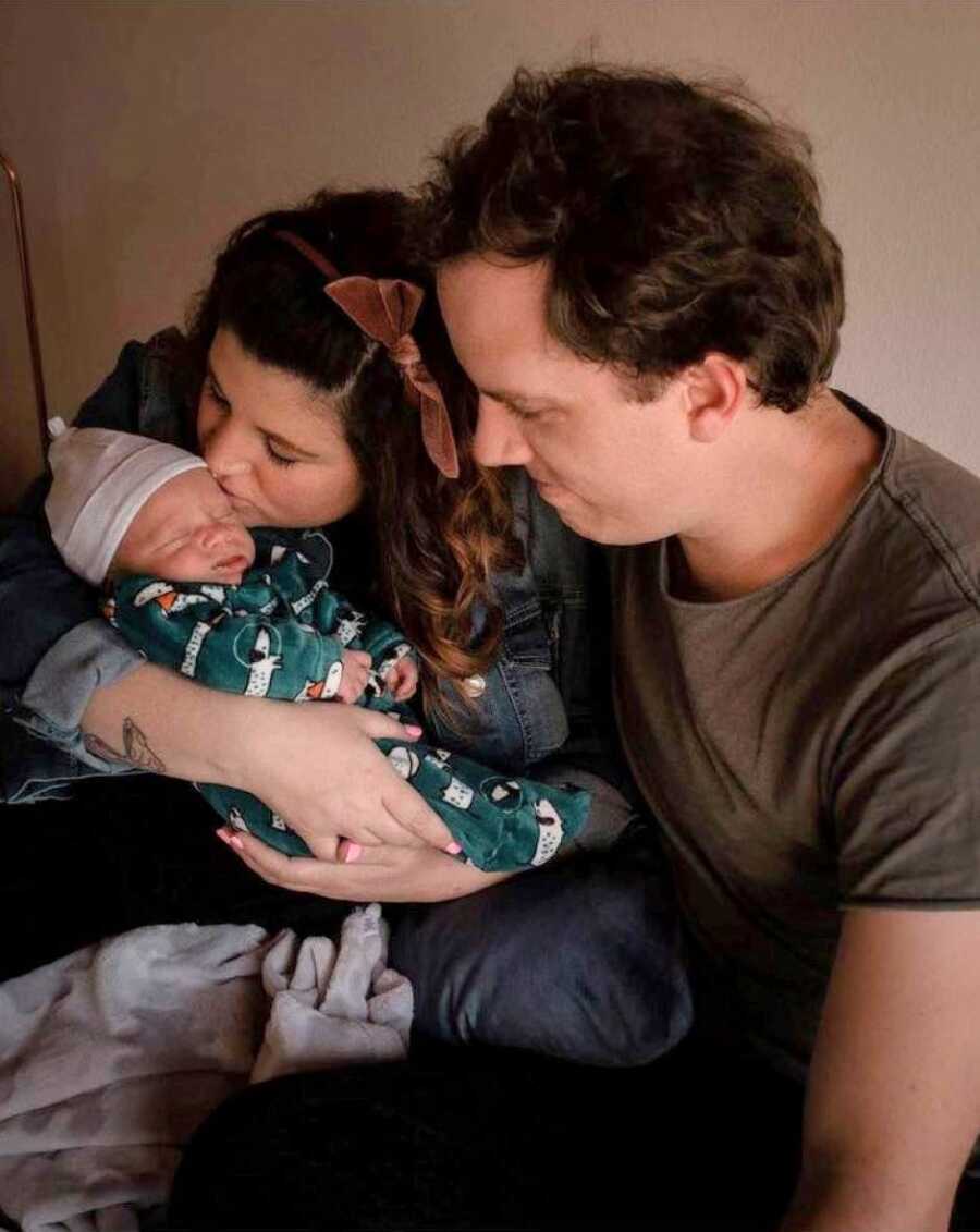 New parents hold their newborn child during newborn photoshoot