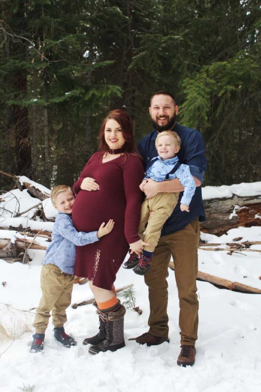 Family of four take photos in the snow while the mom is heavily pregnant with her third child