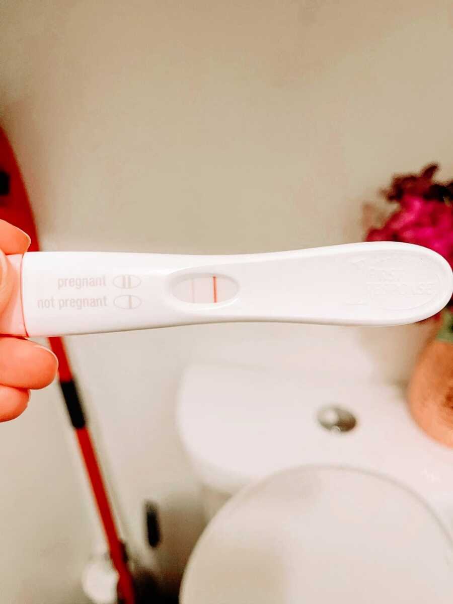 Woman pregnant with her third child takes a photo of a positive pregnancy test