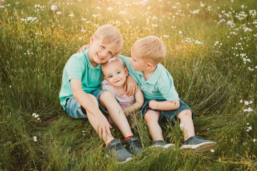 Mom takes a photo of her three children, two boys in matching outfits and one younger daughter