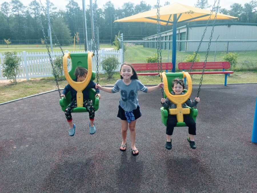 Mom snaps a photo of her three kids playing on the playground together