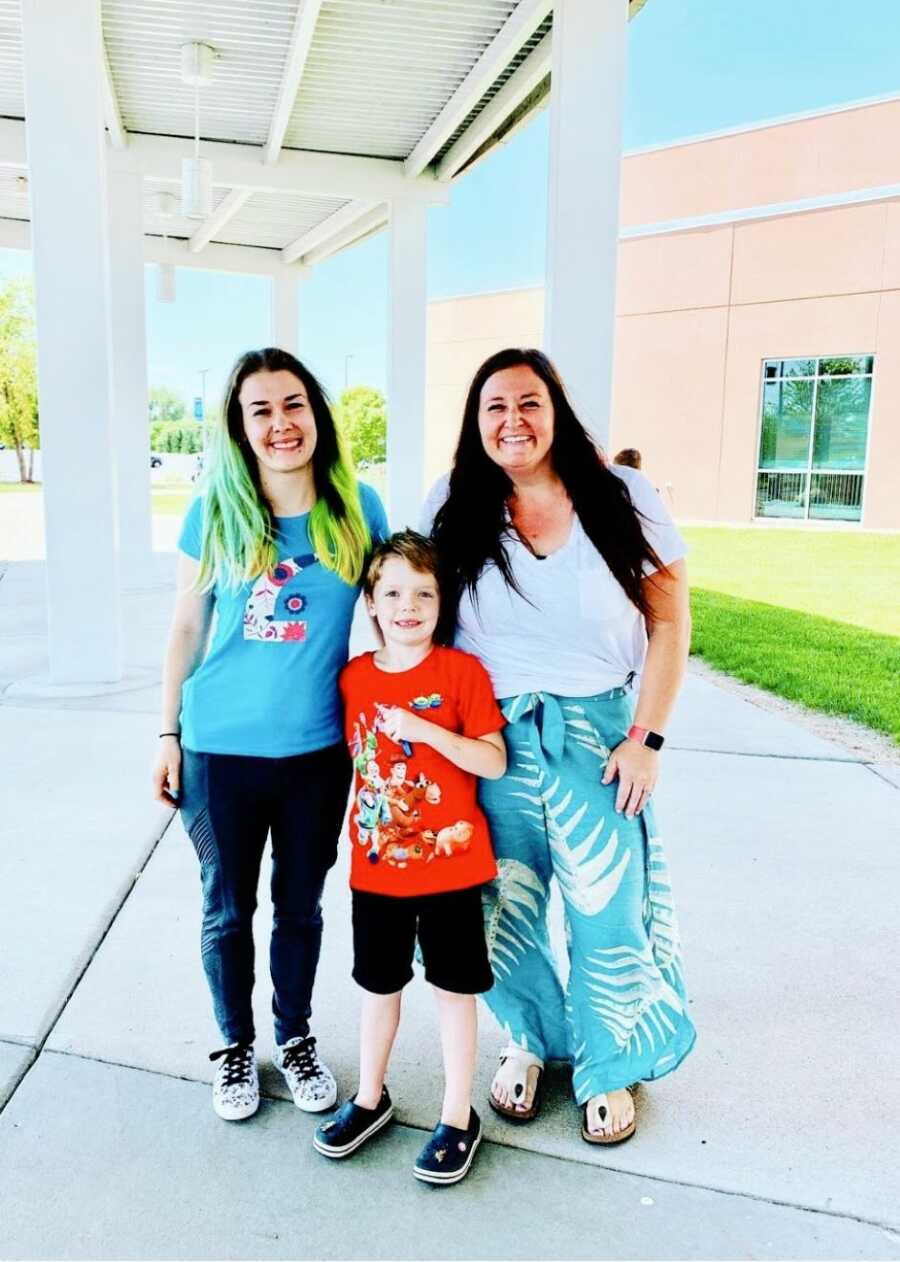 Birth mom and adoptive mom pose with their son during a school function