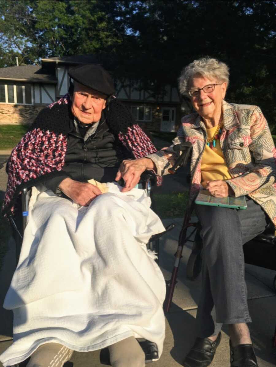 Woman takes a photo of her grandparents as they hold hands while bundled up in coats during wintertime