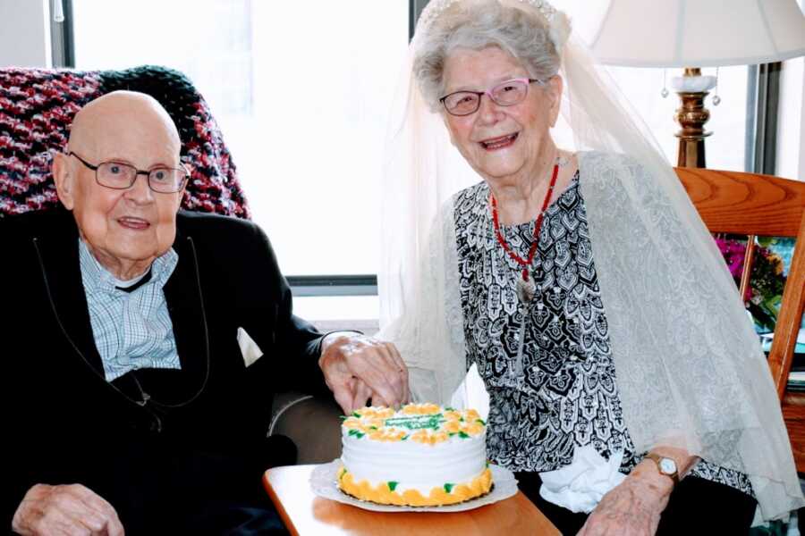 一对老夫妇在庆祝他们的结婚75周年纪念日时，手牵着手微笑着拍照，然后享受一块蛋糕