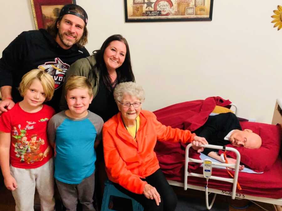 Granddaughter takes a photo with her grandparents, husband, and children while visiting her grandpa in hospice care