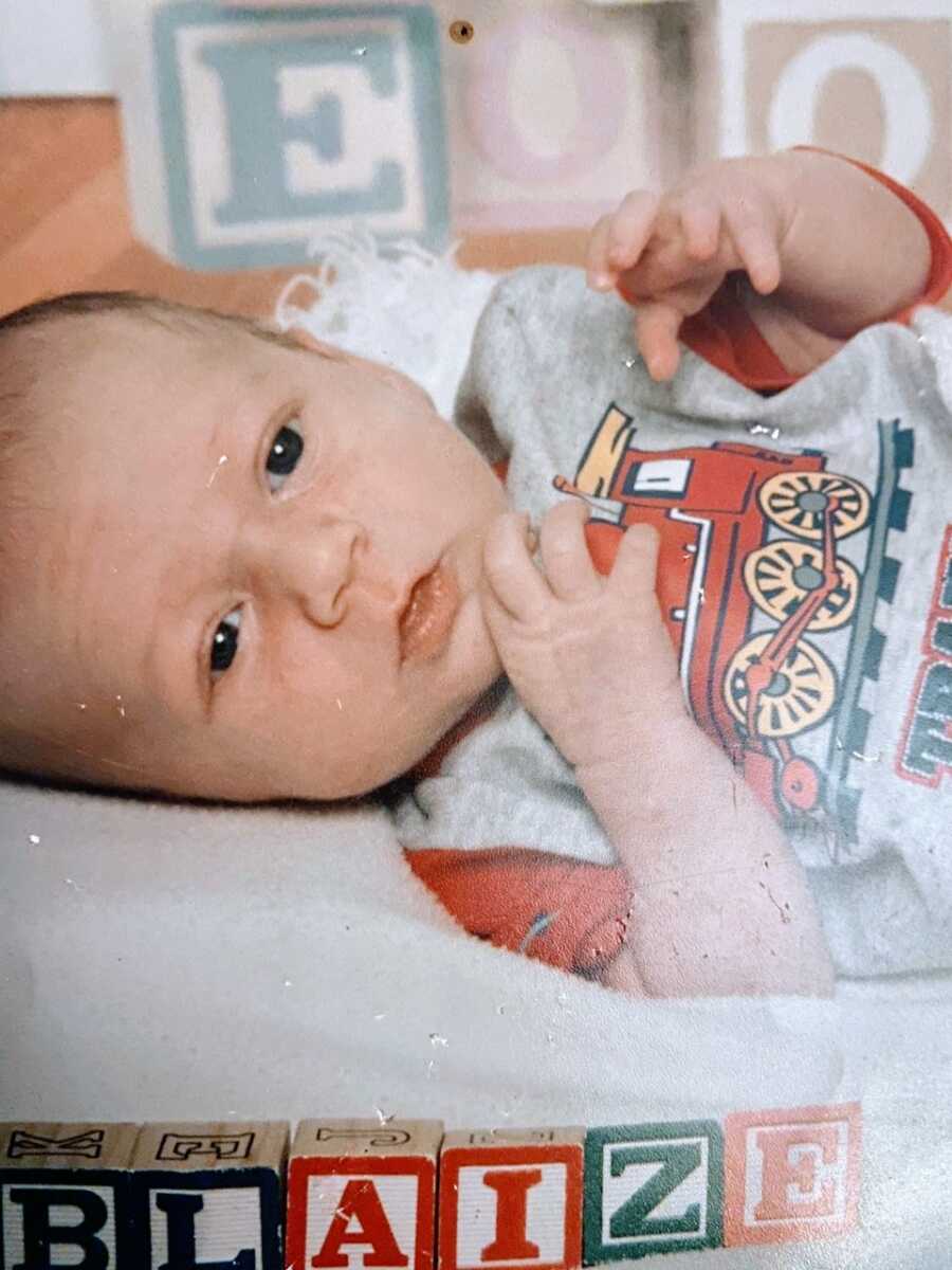 Teen mom takes a photo of her newborn son in a red and gray shirt with a train on it