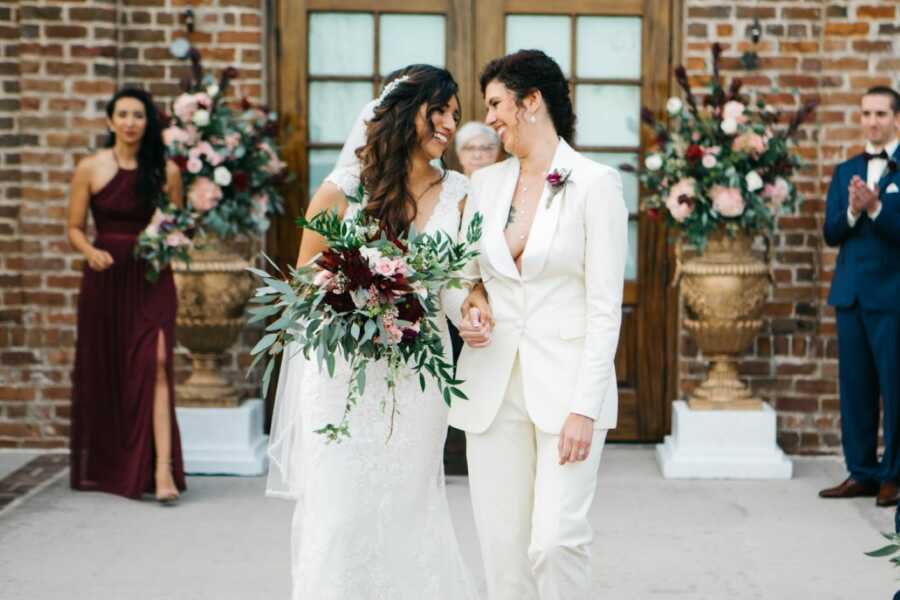 Young married couple smile at each other while walking out onto the dance floor at their wedding reception