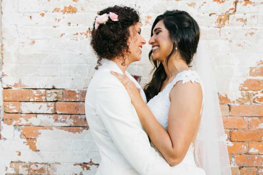 Newlyweds share an intimate moment during their wedding photos, smiling at each other while going in for a kiss