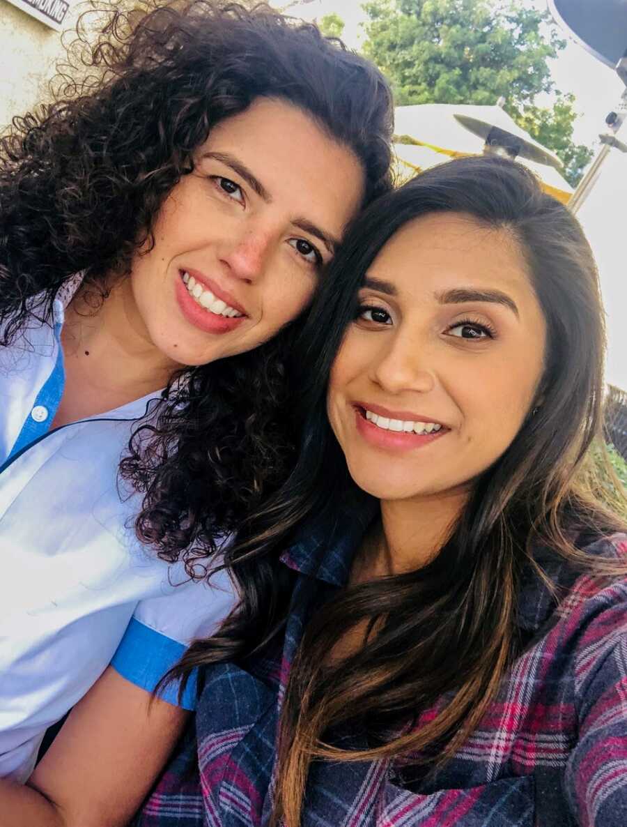 Young lesbian couple, both with brown hair and brown eyes, smile for a selfie while out on a date