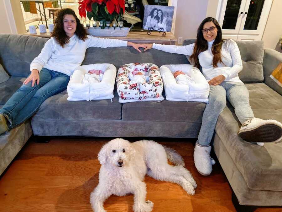 Two moms take a family photo together with their newborn triplets and their family dog