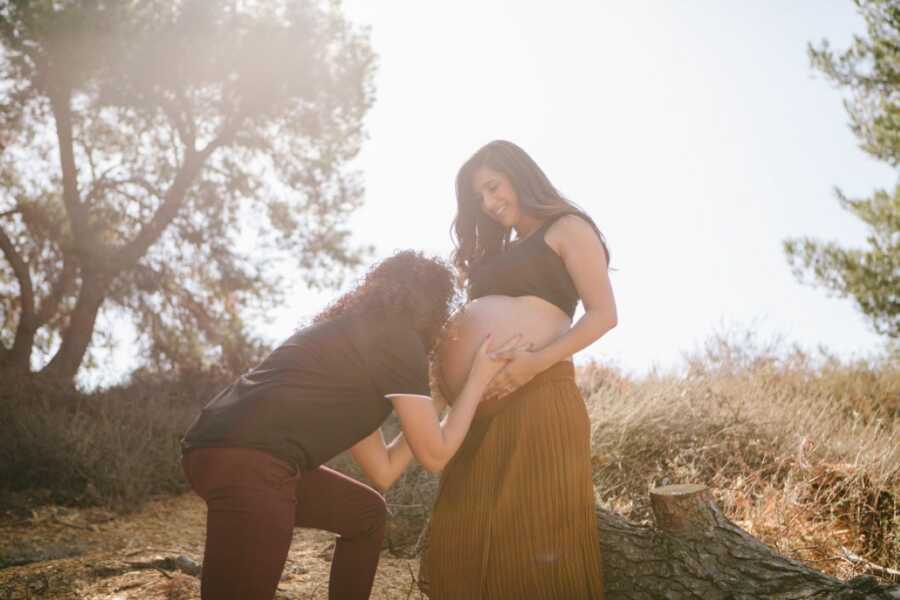 Woman kisses her pregnant wife's baby bump during a maternity photoshoot to announce they're expecting triplets