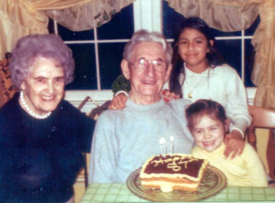 Two young adopted girls take a photo with their grandparents during their grandfather's birthday party