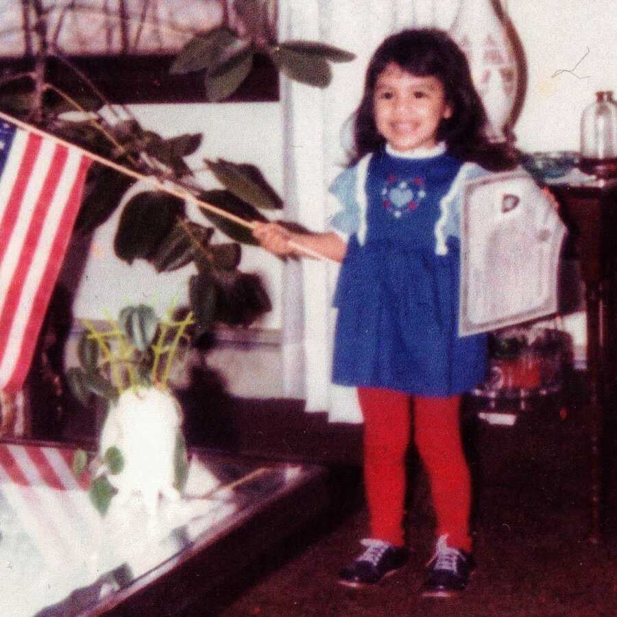 Little girl internationally adopted from Mexico takes a photo with her citizenship certificated and an American flag