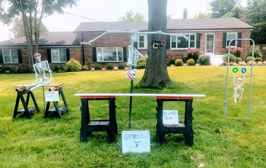 Couple use Halloween skeleton decorations to create a gymnastics yard scene for the Summer Olympics