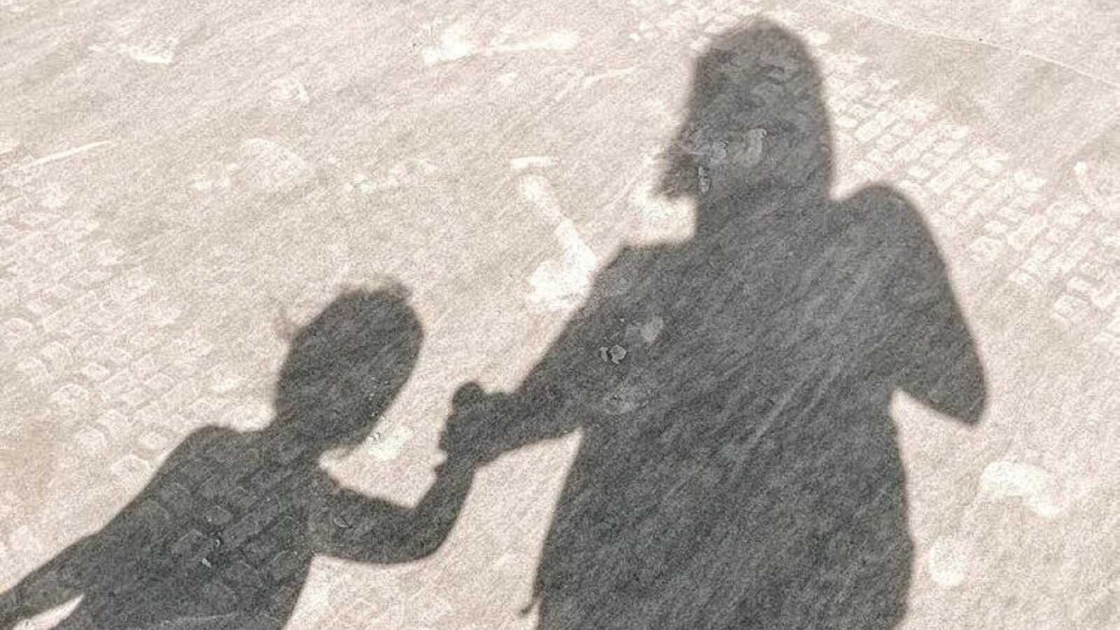 Mom and daughter take a photo of their shadow while walking hand-in-hand