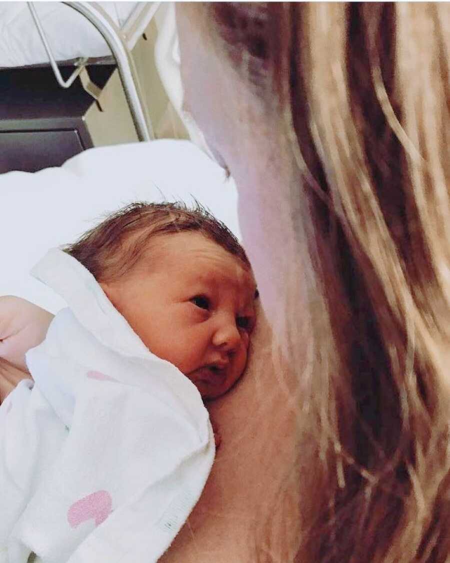 Mom looks down at her newborn daughter while still in the hospital after giving birth