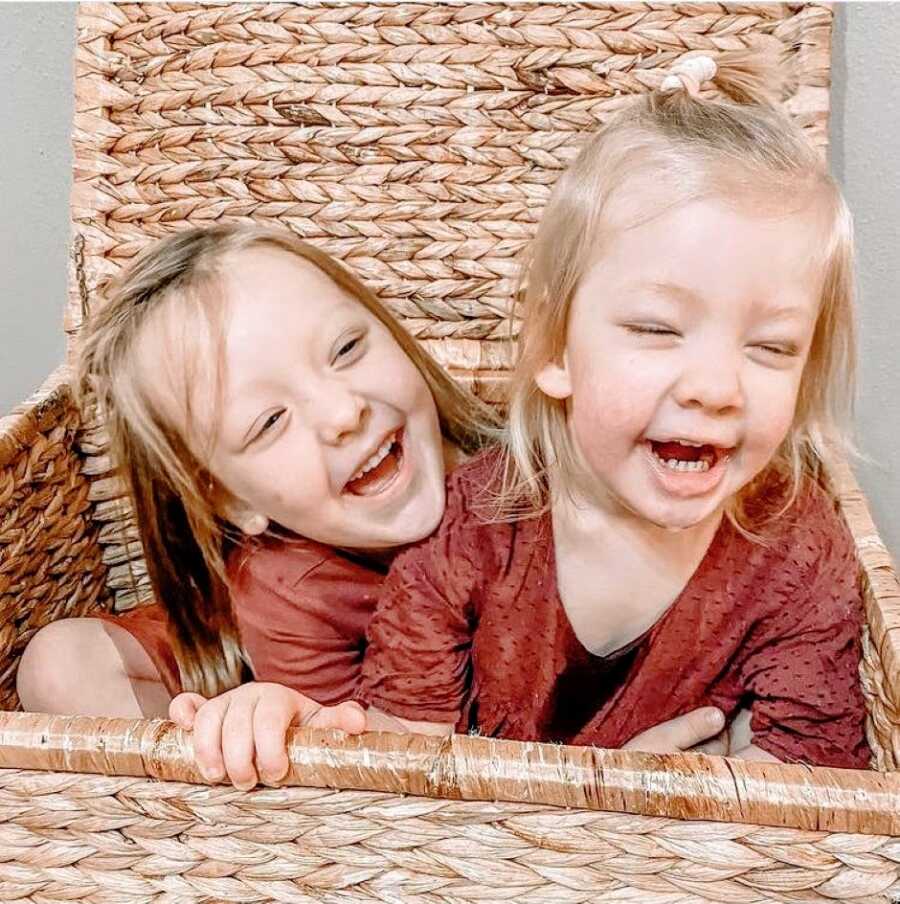 Sisters smile and laugh while playing together in a basket