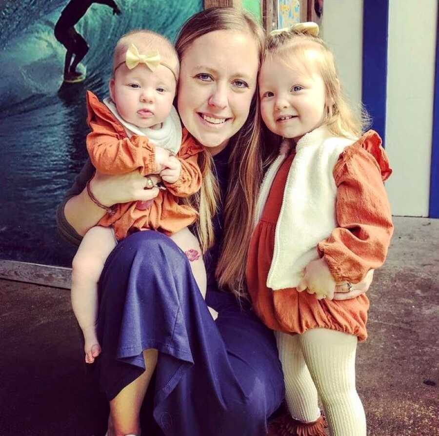 Mom takes a photo with her two daughters wearing matching orange outfits