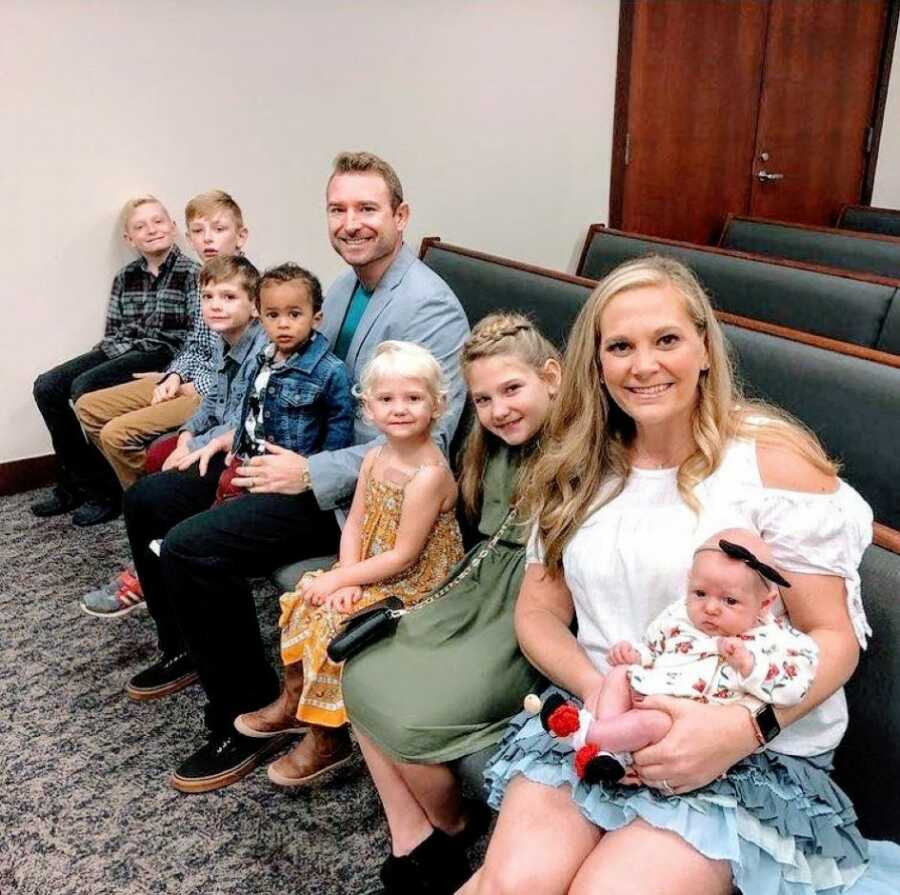 Family of seven take a photo together in a court room on their son's adoption day