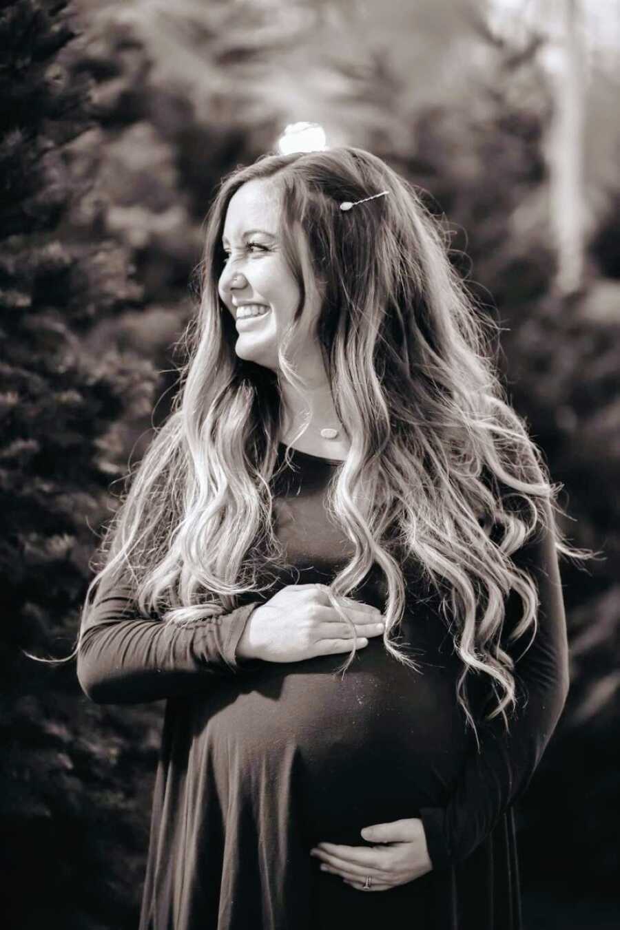 Heavily pregnant woman with severe OCD smiles for a photo while holding her baby bump