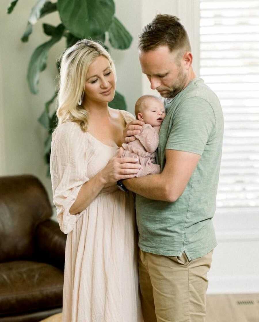 Couple in blended family hold their newborn daughter together