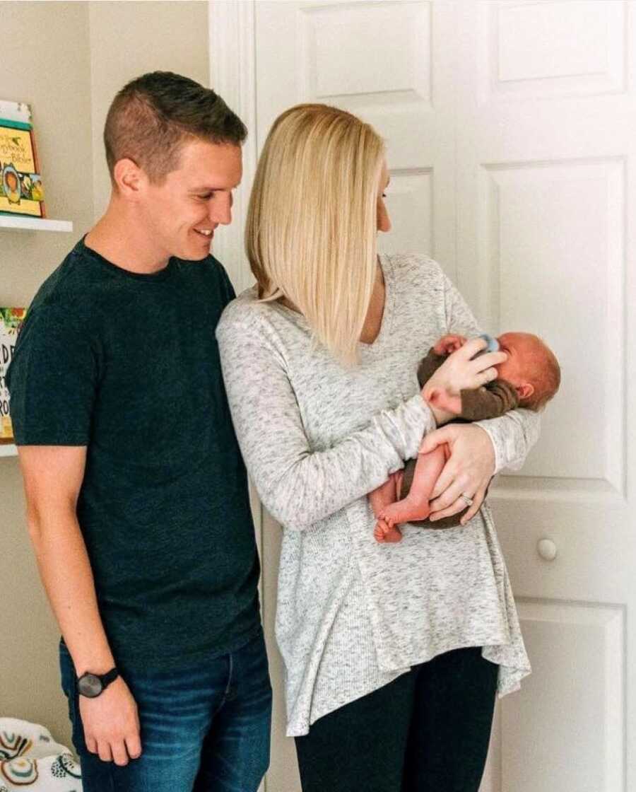 Couple trying years to conceive a child hold their newborn baby in their nursery
