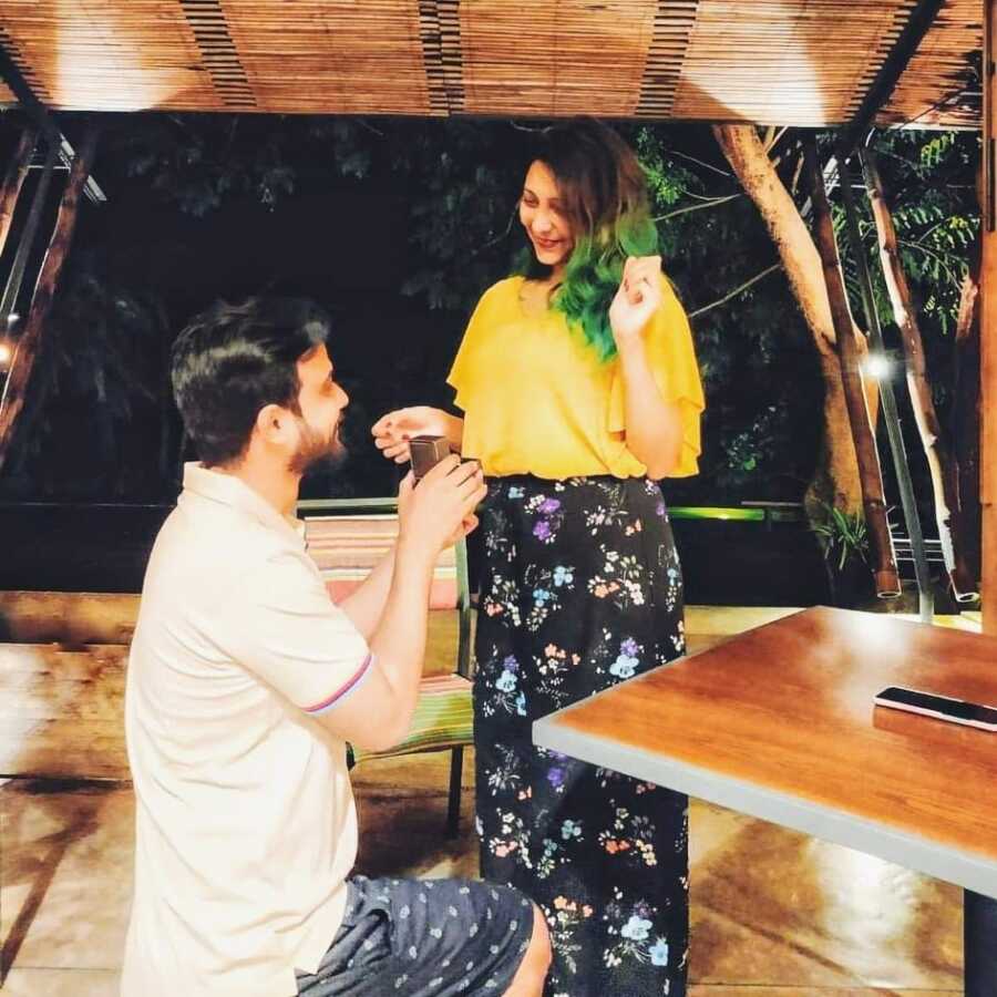 Man gets down on one knee to propose to his wife in romantic setting