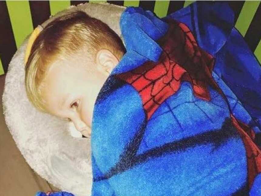妈妈抓住她的儿子的照片睡在他的床上与蜘蛛侠毯子