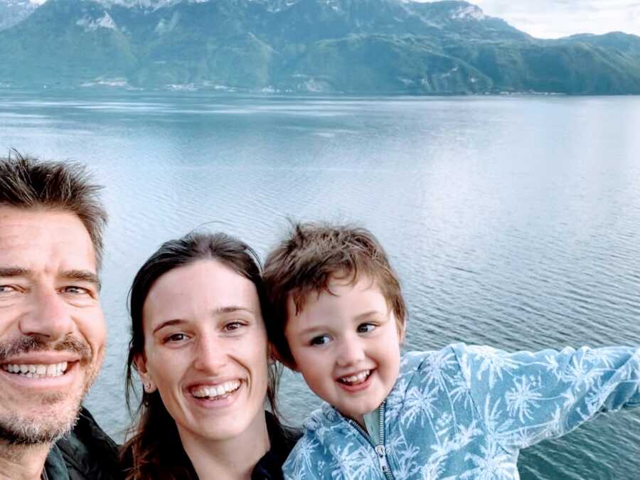 Woman poses for a photo with her boyfriend and son in front of Lake Geneva in Switzerland