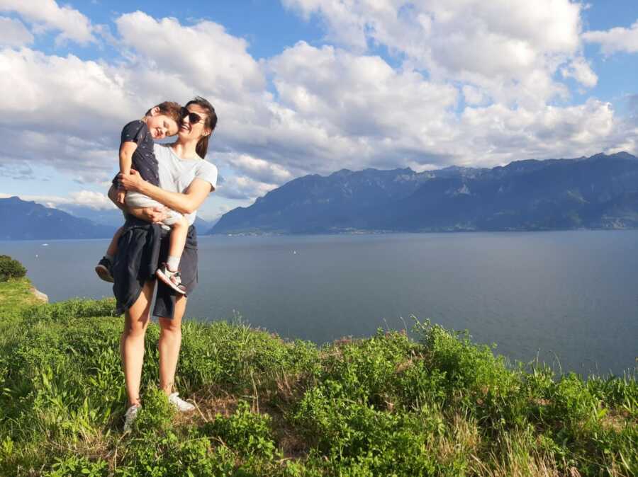 Mom and son pose in front of Lake Geneva in Switzerland, where they have chosen to start over after escaping an abusive situation