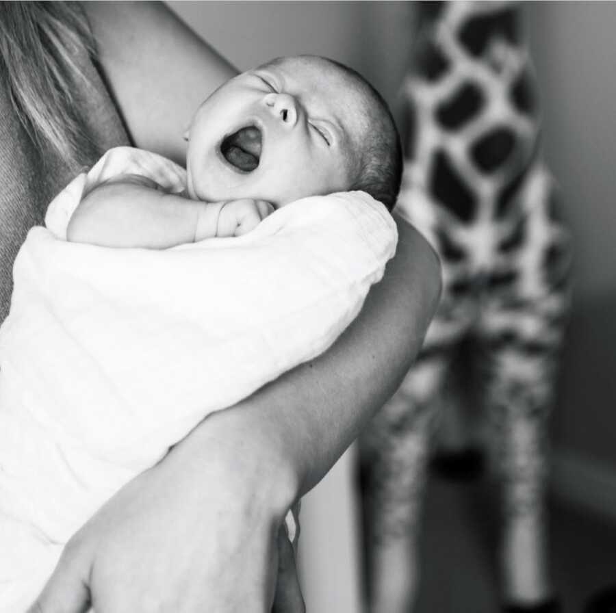 Newborn boy with Down syndrome yawns big during a newborn photoshoot