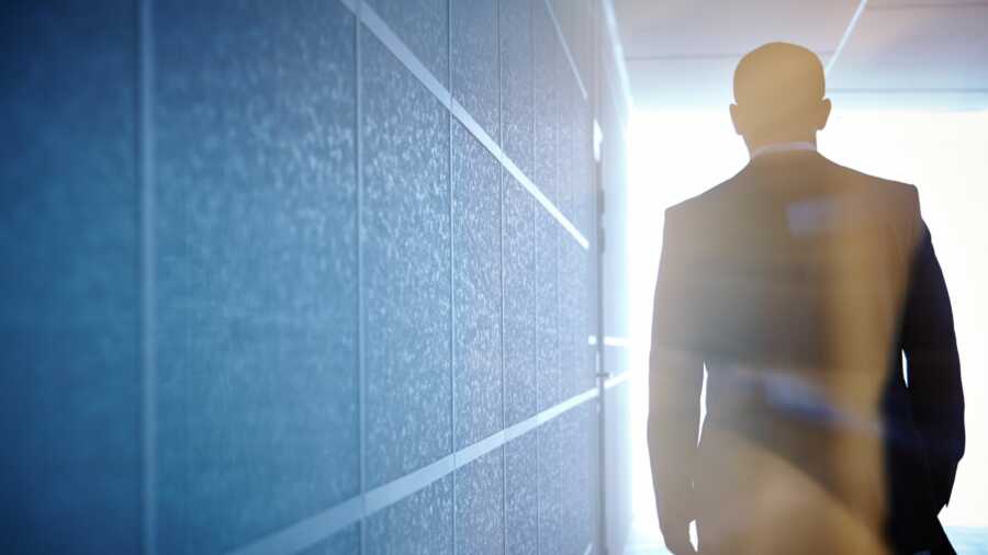 Man walks down an illuminated hallway.