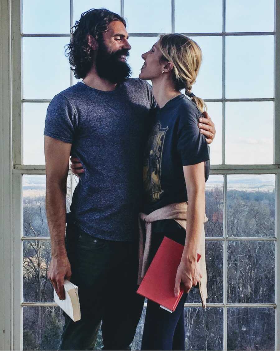 man and woman stand together by window