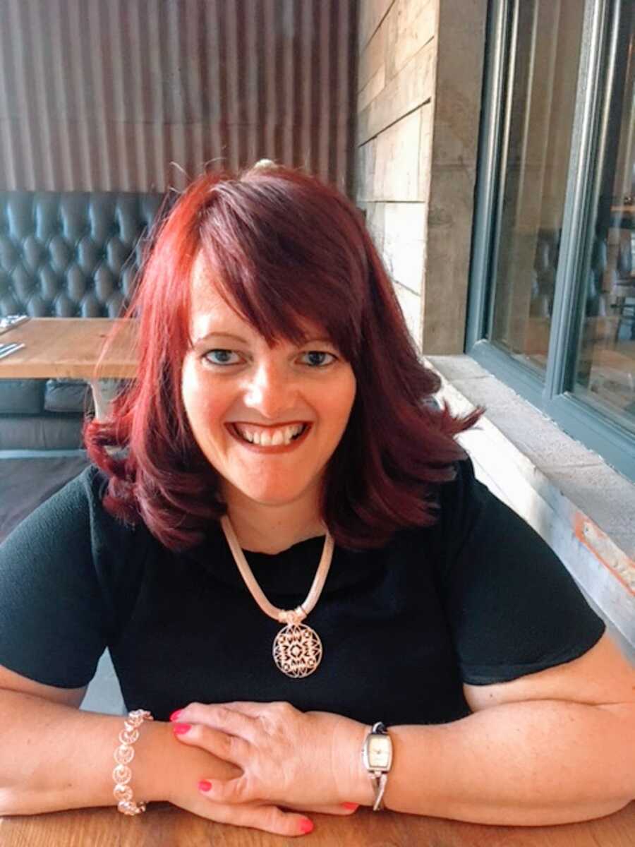 A woman with RSS smiling at a table