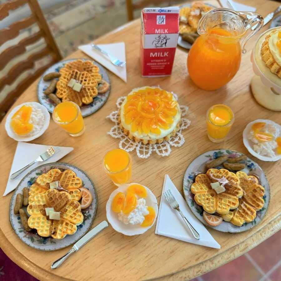 Miniature breakfast waffles and orange juice made from sculpted clay.