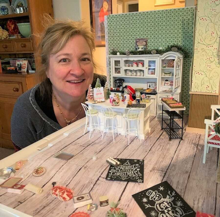 Dianne pictured with one of her miniature dollhouse scenes, decorated for Christmas.