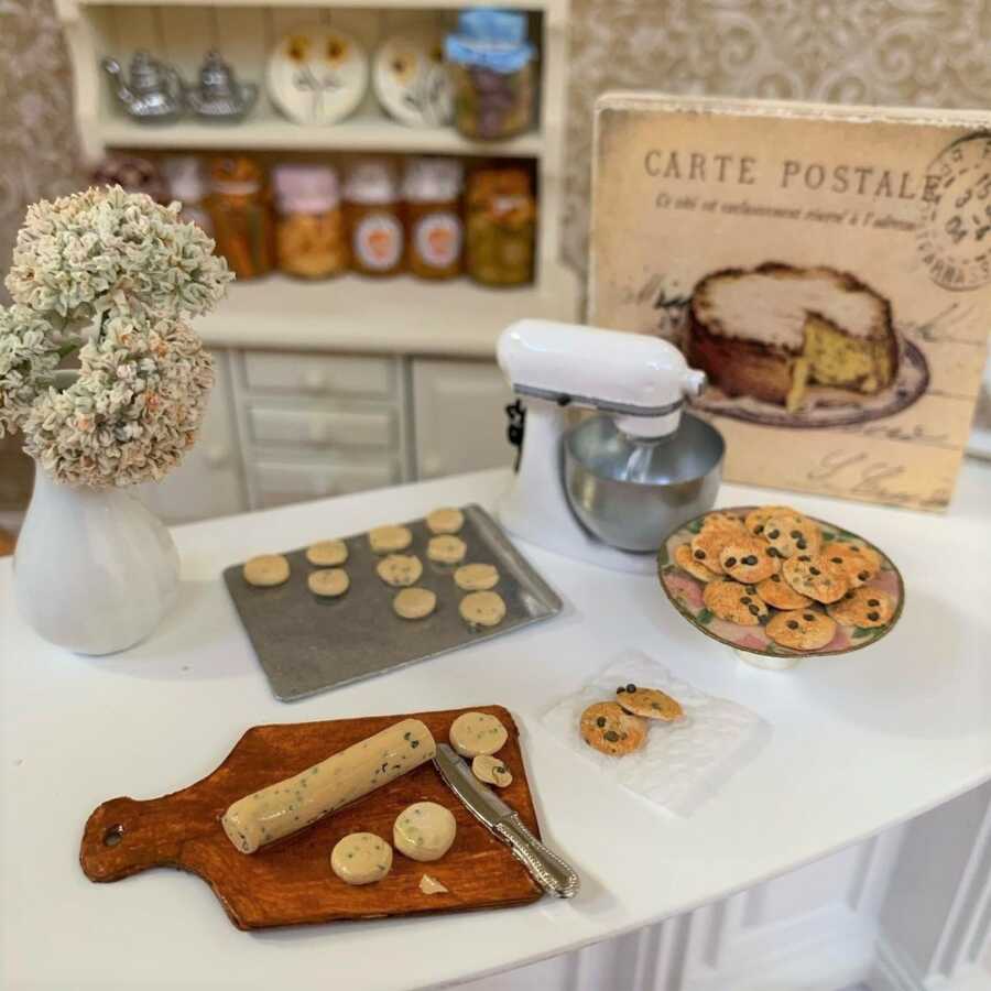 Miniature cookie dough roll and freshly baked cookies made from sculpted clay.