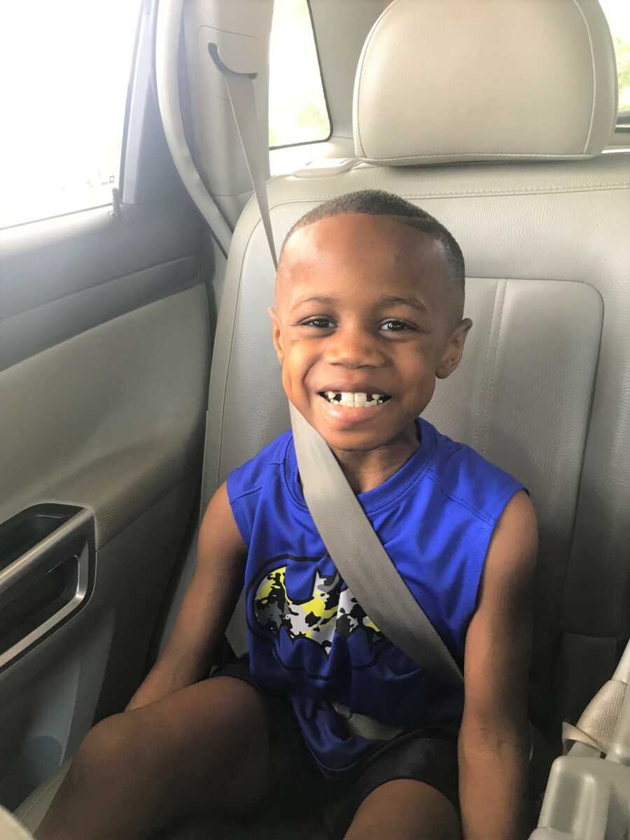 Dwayne sits in the car smiling with his missing teeth.