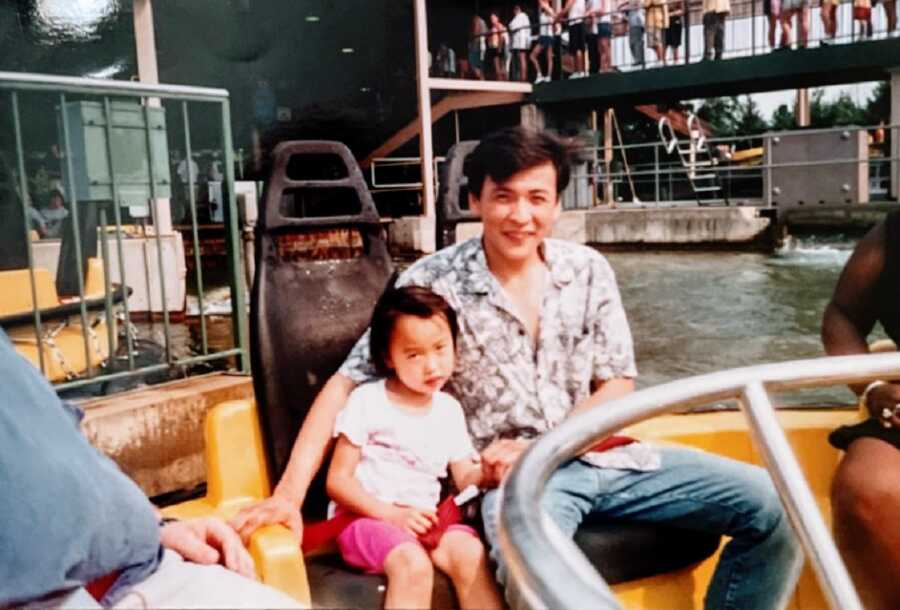 Little girl with cerebral palsy sits with father on ride